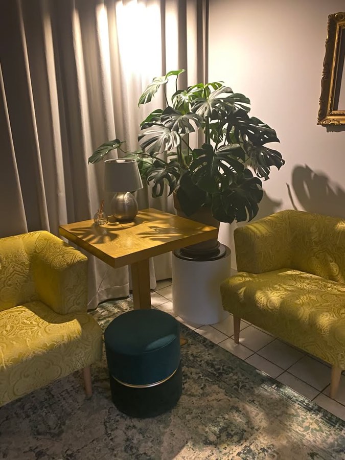 Posezení ve studiu — žlutá křesla, monstera a lampa v teplém večerním světle