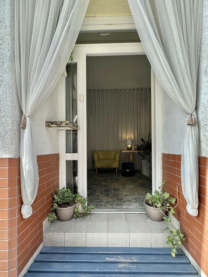 Vchod do studia se závěsy a květinami u schodů